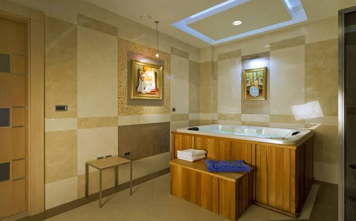 Monte Casa Spa & Wellness privātā spa zona ar koka apdares džakuzi vannu, mākslas darbiem pie sienām un modernu apgaismojumu