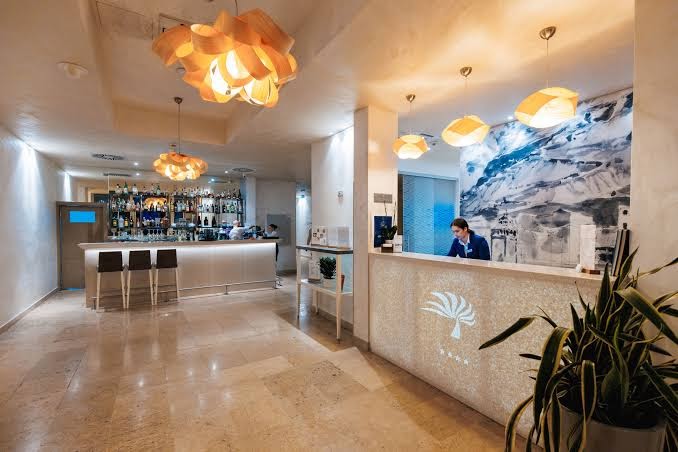 Hotel Palma recepcijas zona un bārs ar modernu apgaismojumu, gaišām flīzēm un viesmīlīgu personālu