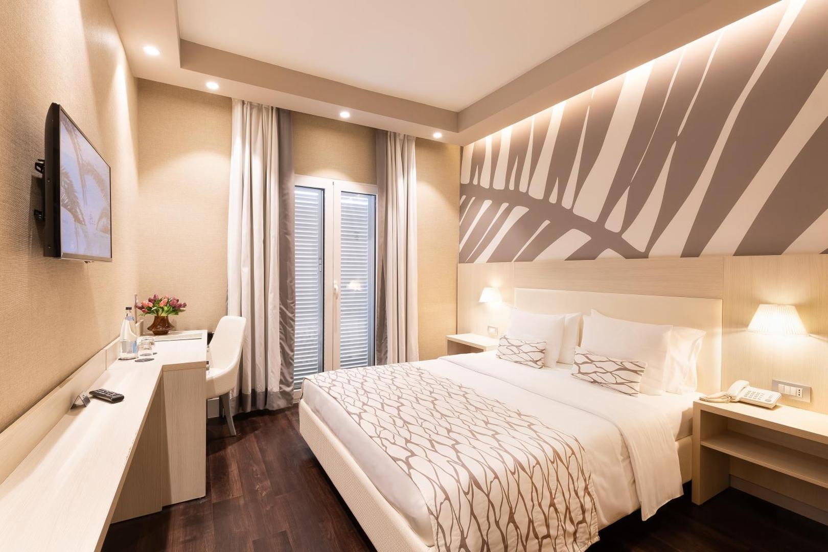 Hotel Palma moderns divvietīgs numurs ar gaišu interjeru, koka grīdu, darba zonu un dekoratīvu sienas paneli
