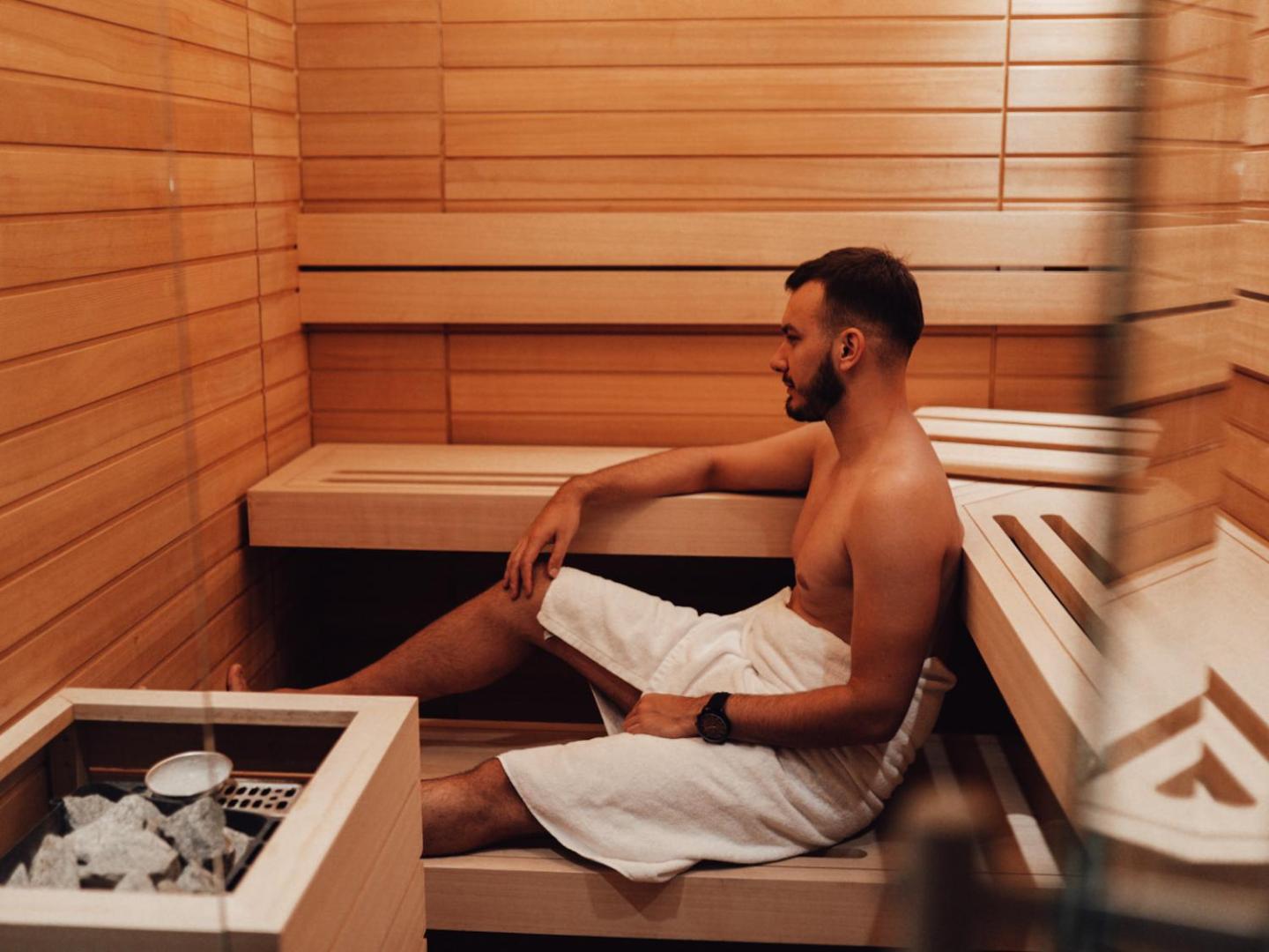 Vīrietis atpūšas Hotel Fagus by Aycon koka apdares saunā, baudot mierīgu brīdi viesnīcas spa zonā