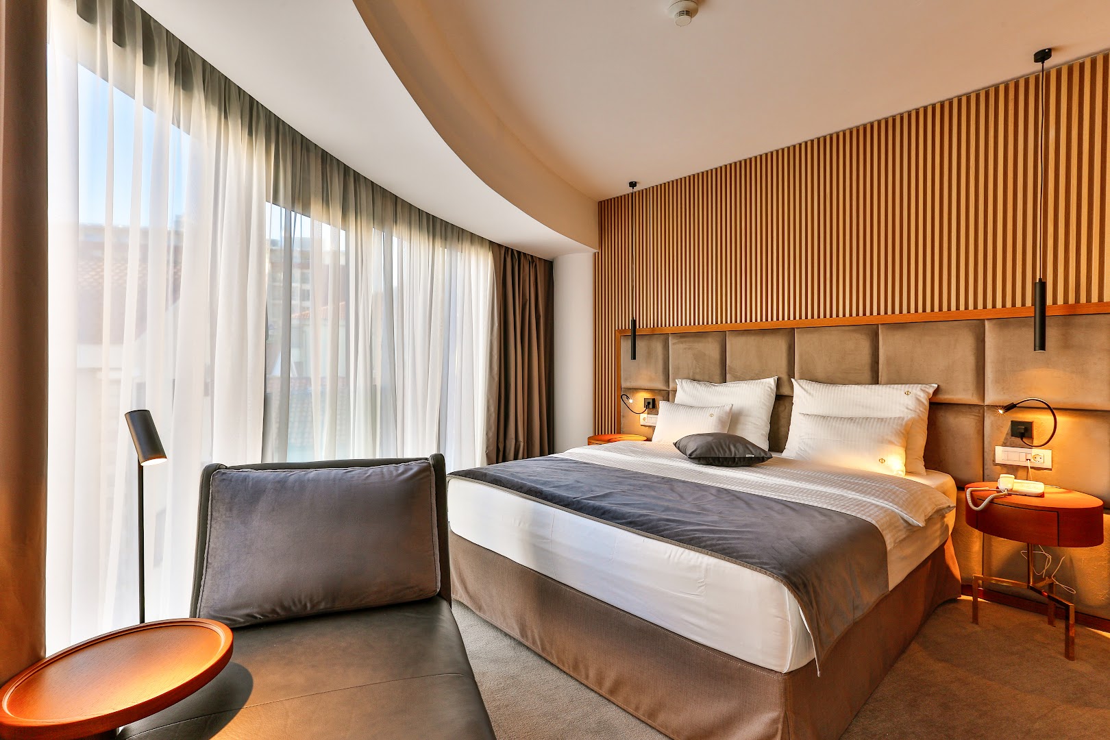 Hotel Fagus by Aycon elegants viesnīcas numurs ar lielu gultu, koka paneļu sienu un panorāmas logiem gaišos toņos