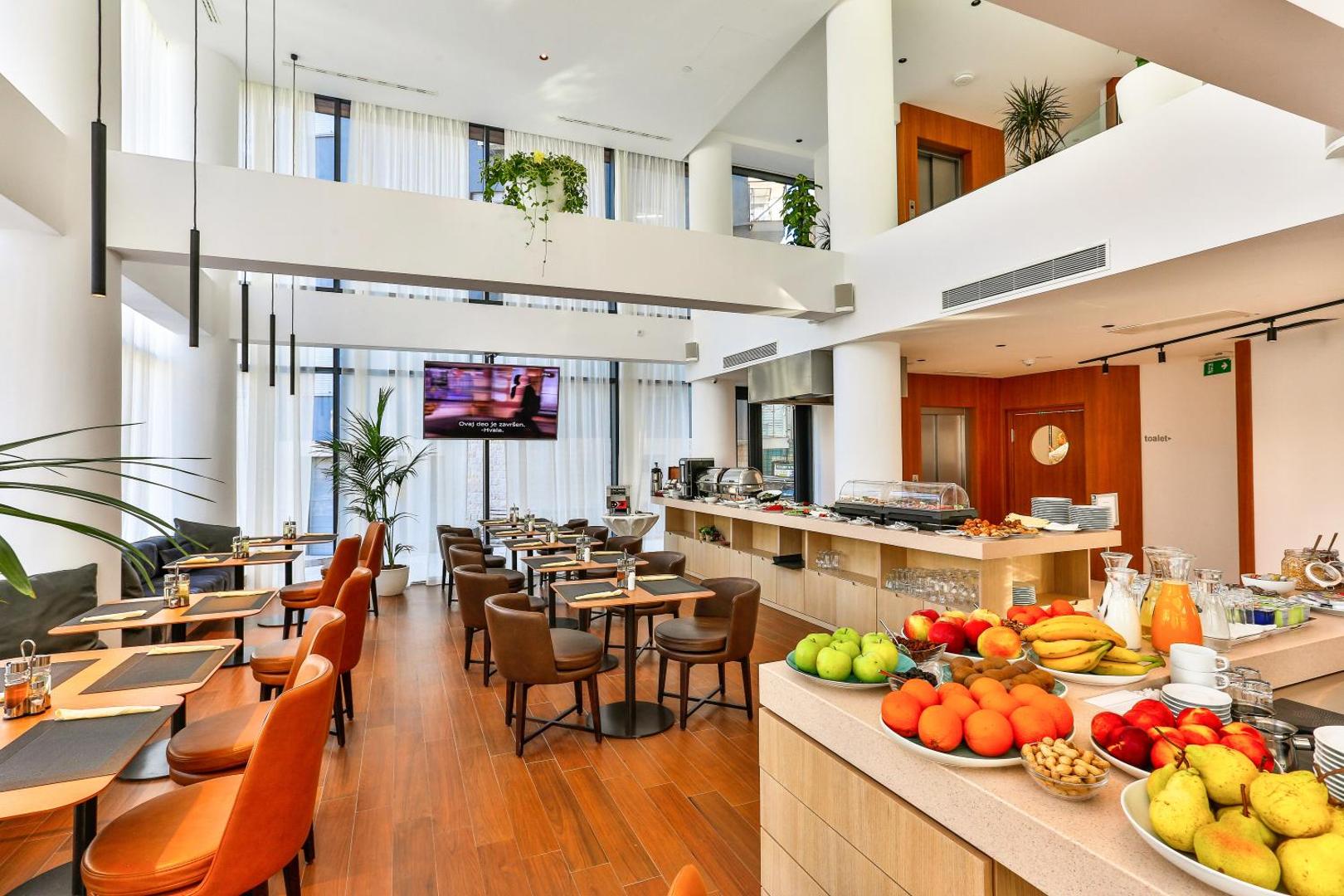 Hotel Fagus by Aycon restorāna kopskats ar brokastu galdiem, svaigiem augļiem un modernu dizainu divos stāvos
