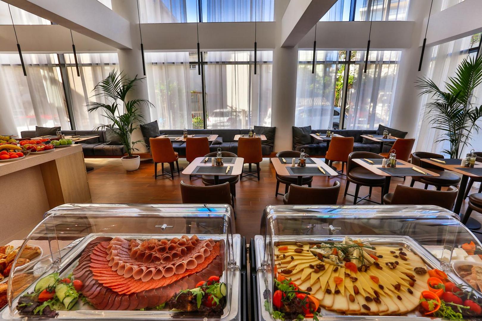Hotel Fagus by Aycon restorāna brokastu bufete ar plašu sieru un gaļas izlasi — gaišs un moderns interjers
