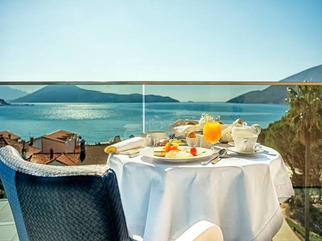 Brokastu galds uz Palmon Bay Hotel & SPA balkona ar skatu uz jūru, kalniem un piekrastes pilsētu