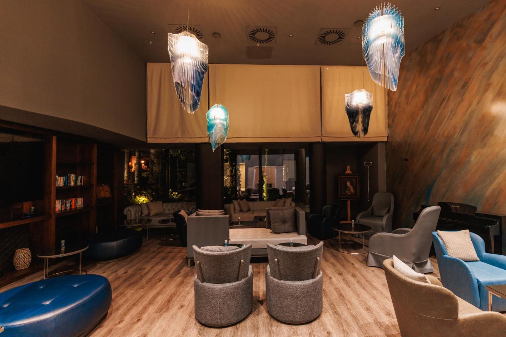 Palmon Bay Hotel & SPA mājīga atpūtas zona ar mīkstiem krēsliem, dizaina gaismekļiem un grāmatu plauktu Igalo kūrortā, Melnkalnē
