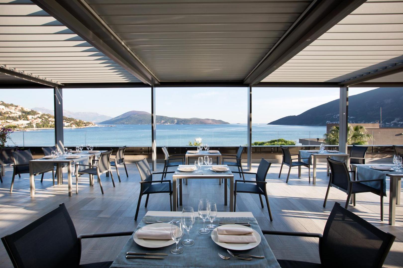 Palmon Bay Hotel & SPA restorāna āra terase ar galdiņiem un panorāmas skatu uz Adrijas jūru un kalniem dienas gaismā