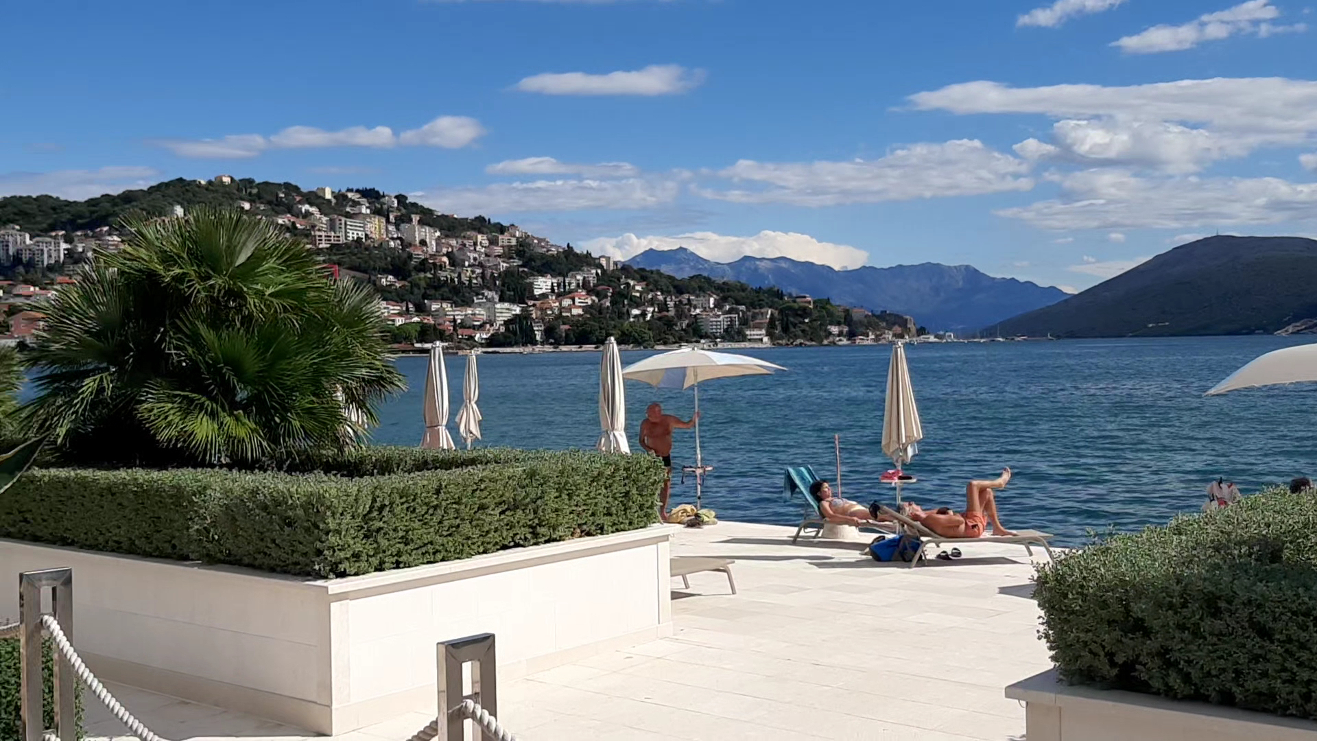Palmon Bay Hotel & SPA āra terase ar atpūtas krēsliem un skatu uz jūru, kalniem un pilsētas piekrasti