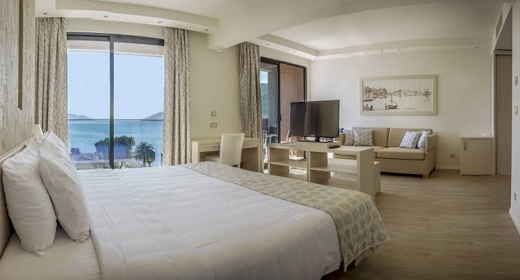 Palmon Bay Hotel & SPA gaišs viesnīcas numurs ar lielu gultu, dīvānu un skatu uz Adrijas jūru pa logu
