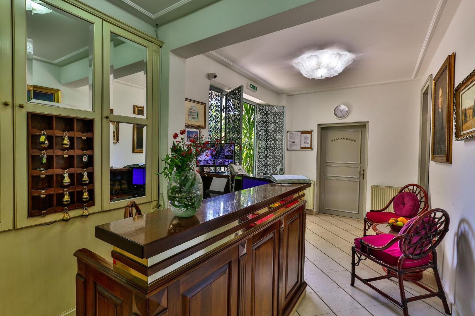 Villa Velzon viesnīcas recepcijas zona ar koka leti un klasisku interjeru Budvā — mājīga uzņemšanas telpa viesiem