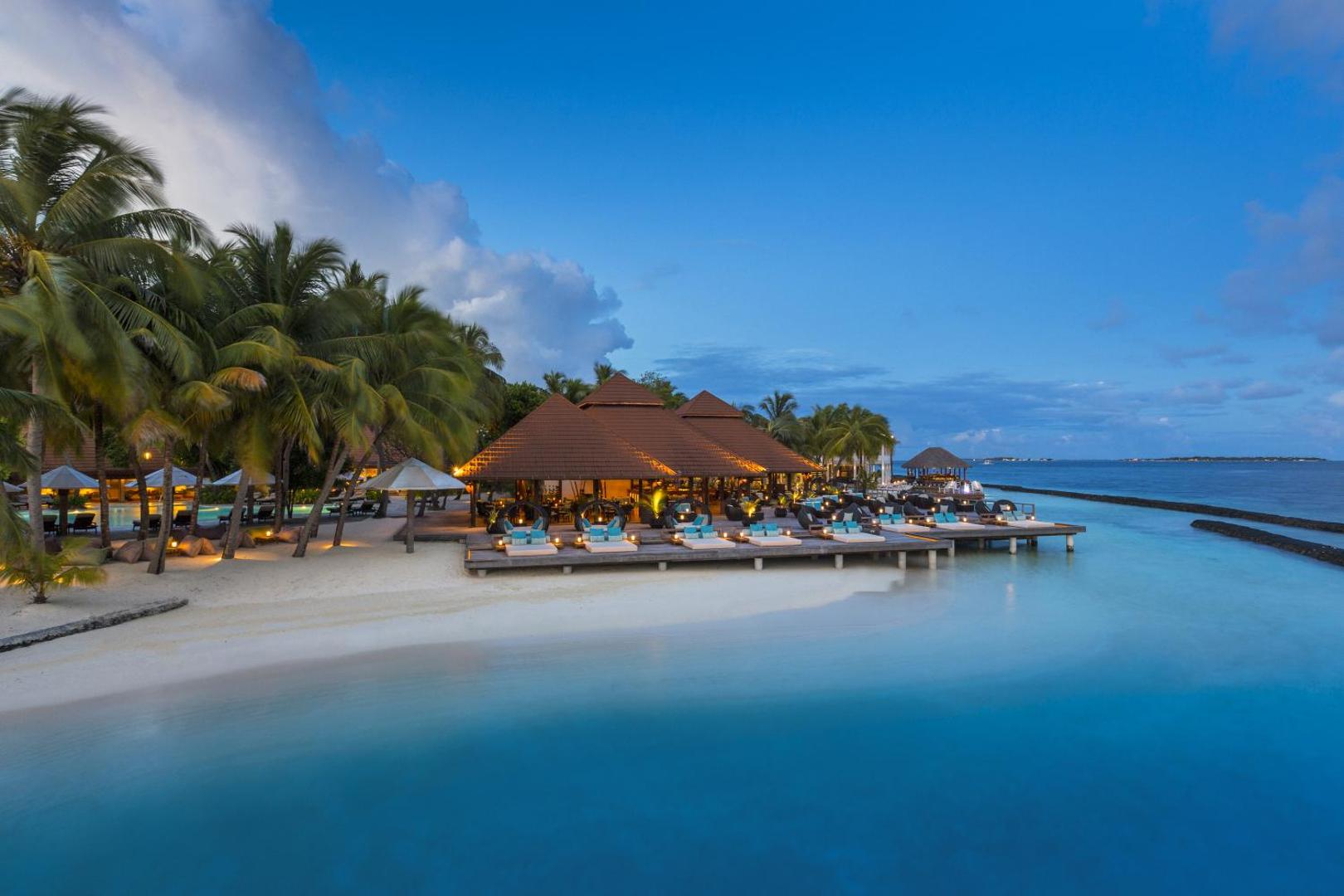 Niva Kurumba Maldives bārs un atpūtas terase virs ūdens saulrieta laikā ar mīkstiem zviļņiem un apgaismojumu