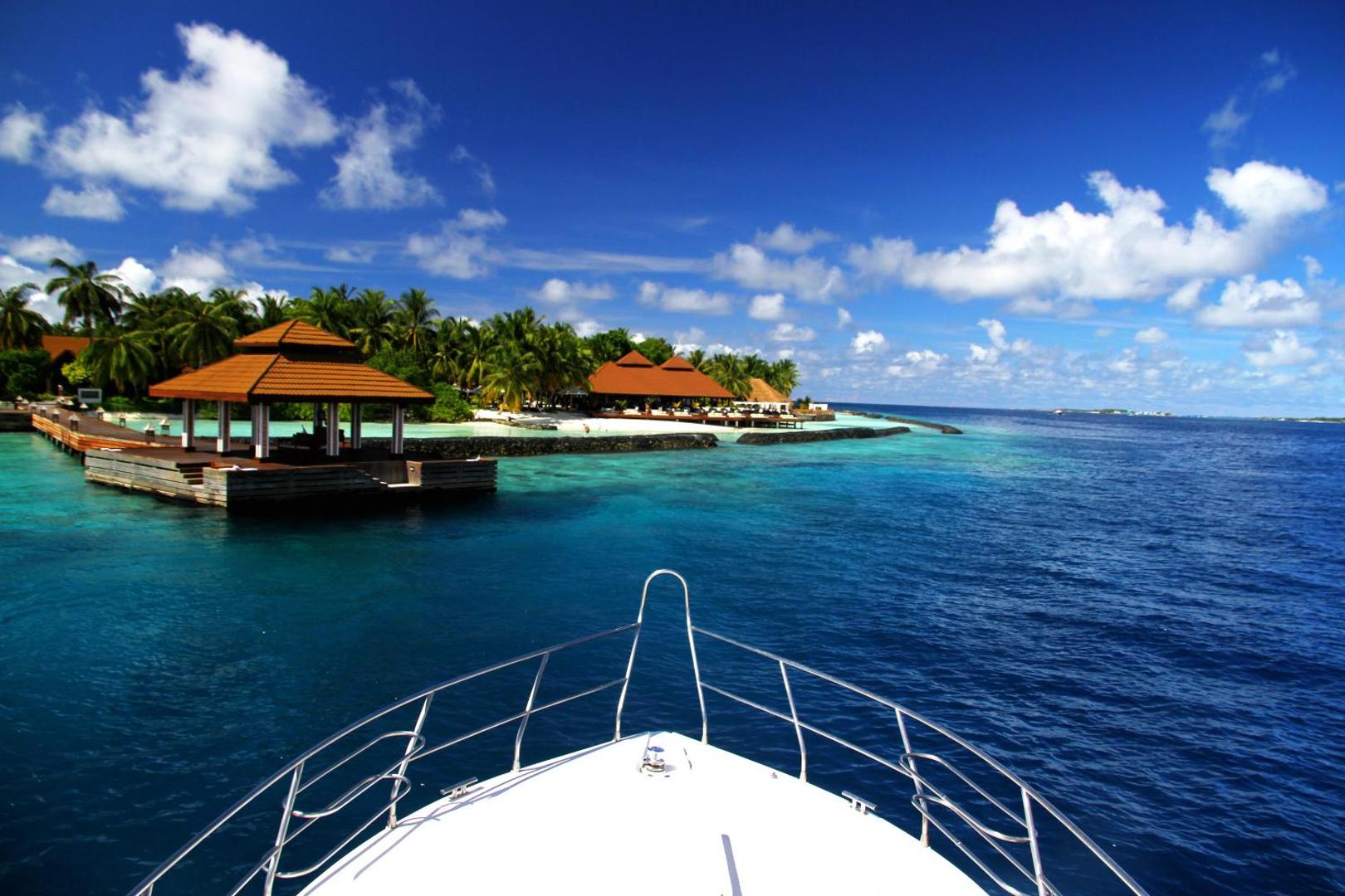 Skats no kutera priekšgala uz Niva Kurumba Maldives kūrorta piestātni un piekrastes bungalo Maldīvu salu dzidrajos ūdeņos