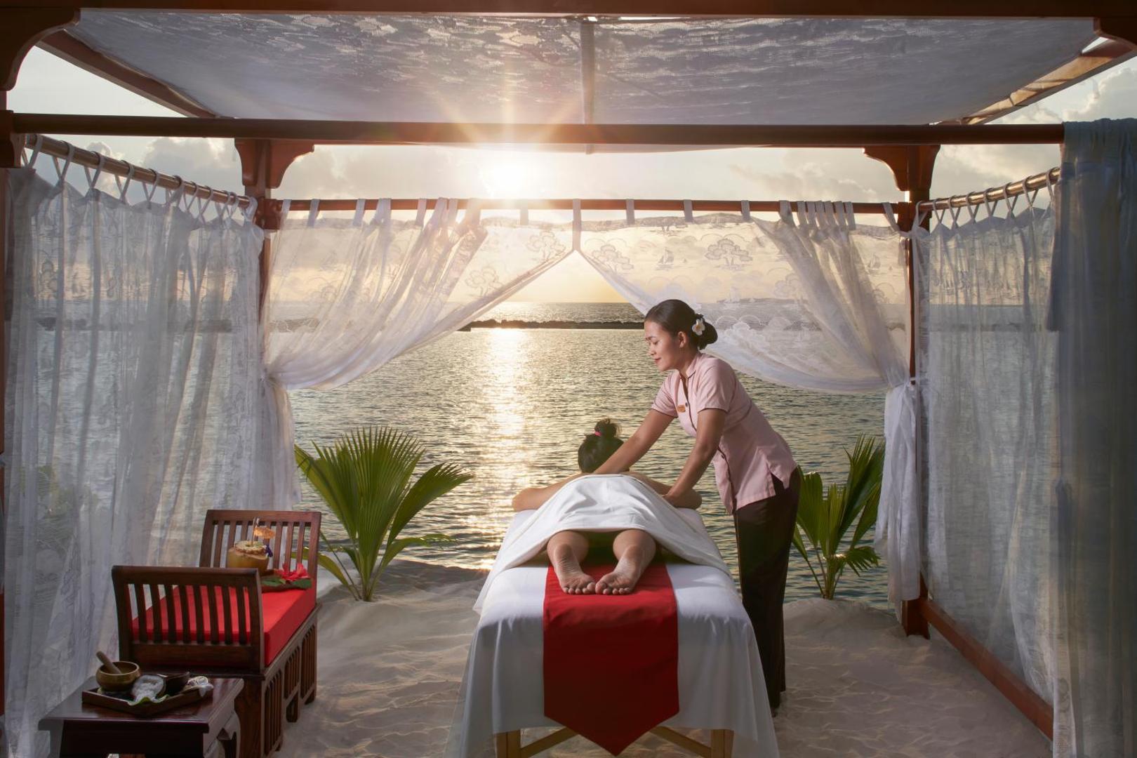 Relaksējoša masāža spa teltī Royal Island Resort & Spa pludmalē Maldīvās saulrieta laikā ar skatu uz jūru
