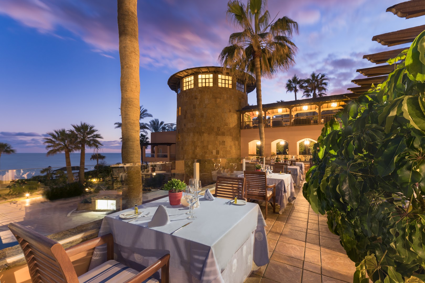 Elba Estepona Gran Hotel vakara skats uz restorāna terasi un vēsturiska stila torni saulrieta laikā pie jūras Spānijā