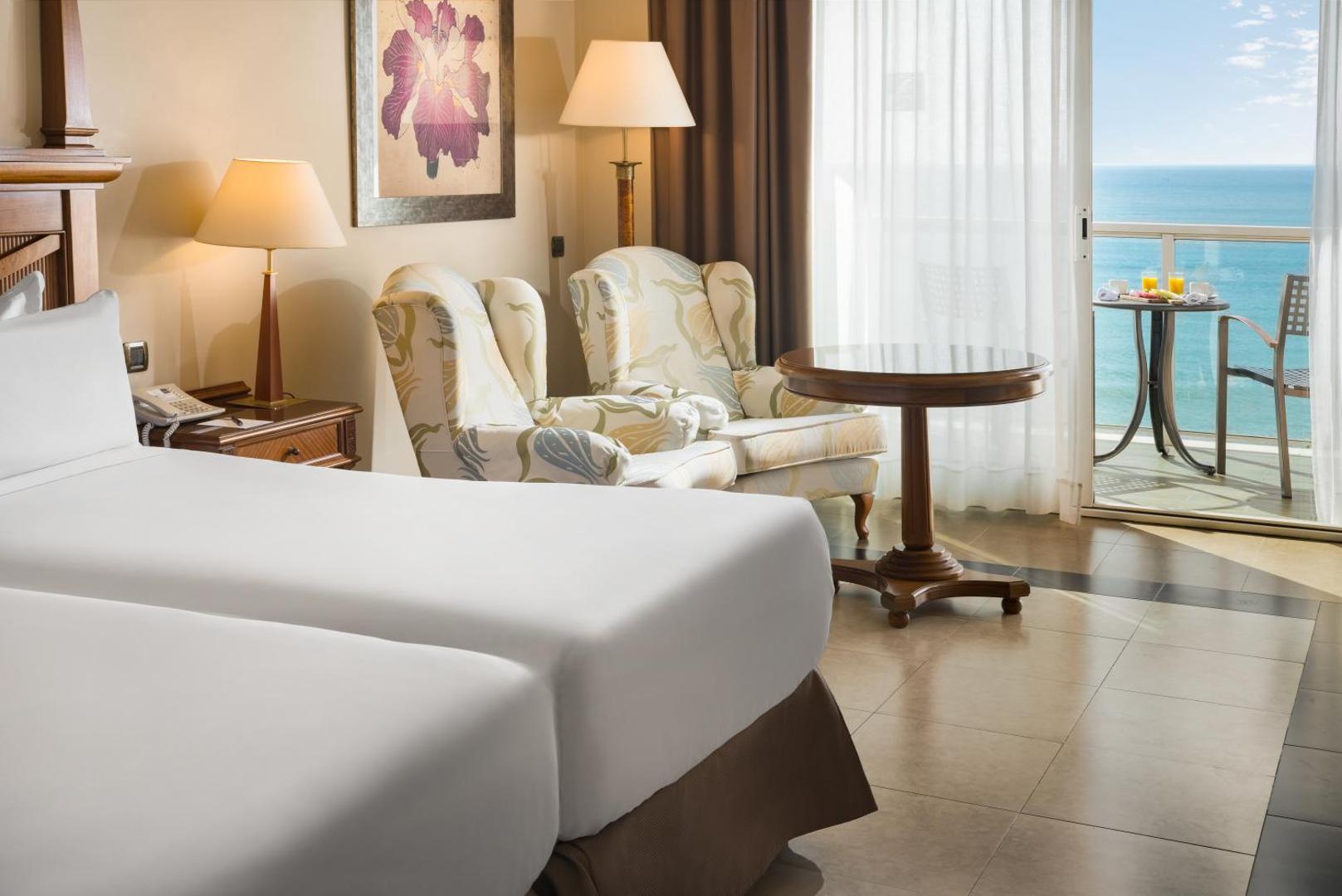 Gaišs Elba Estepona Gran Hotel numura interjers ar atpūtas zonu, divām gultām un balkonu, no kura paveras skats uz jūru