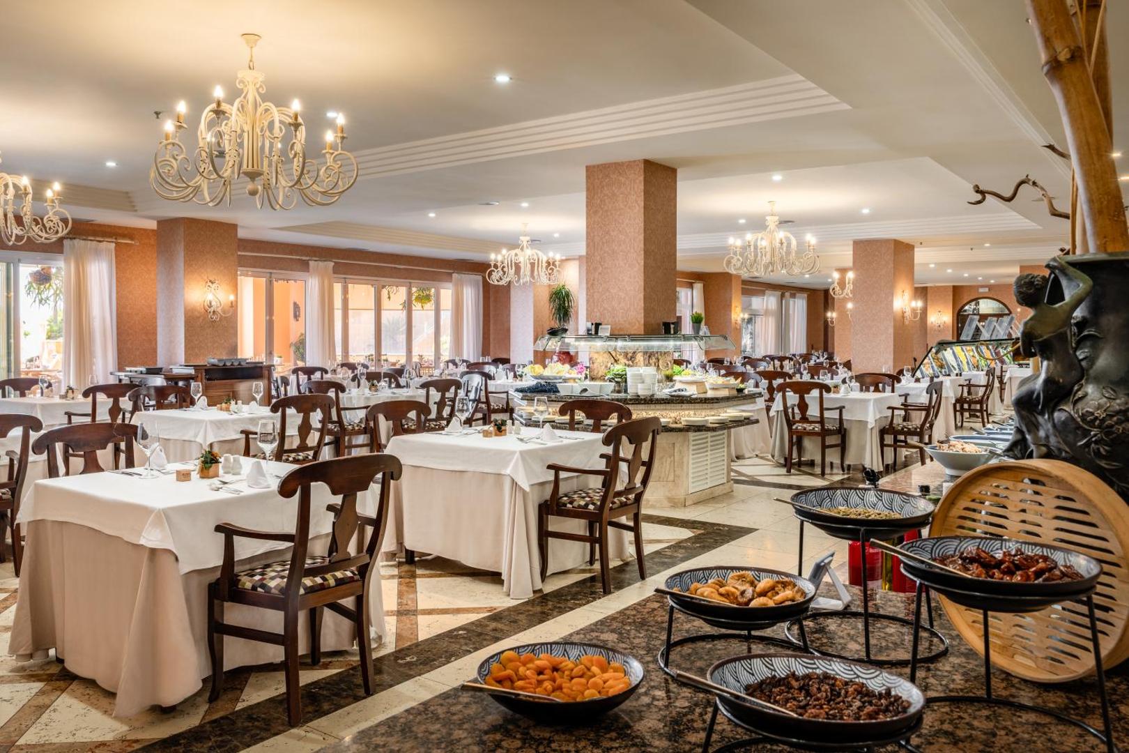 Elba Estepona Gran Hotel galvenais restorāns ar bagātīgu bufetes izvēli, klasiskām koka mēbelēm un greznām lustrām