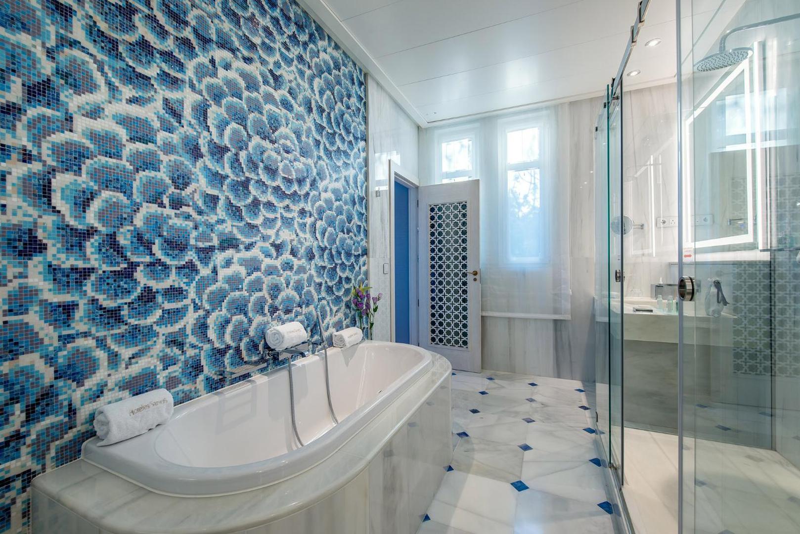 Gran Hotel Miramar vannas istaba ar zilu mozaīkas sienu, brīvstāvošu vannu un stikla dušas kabīni modernā stilā