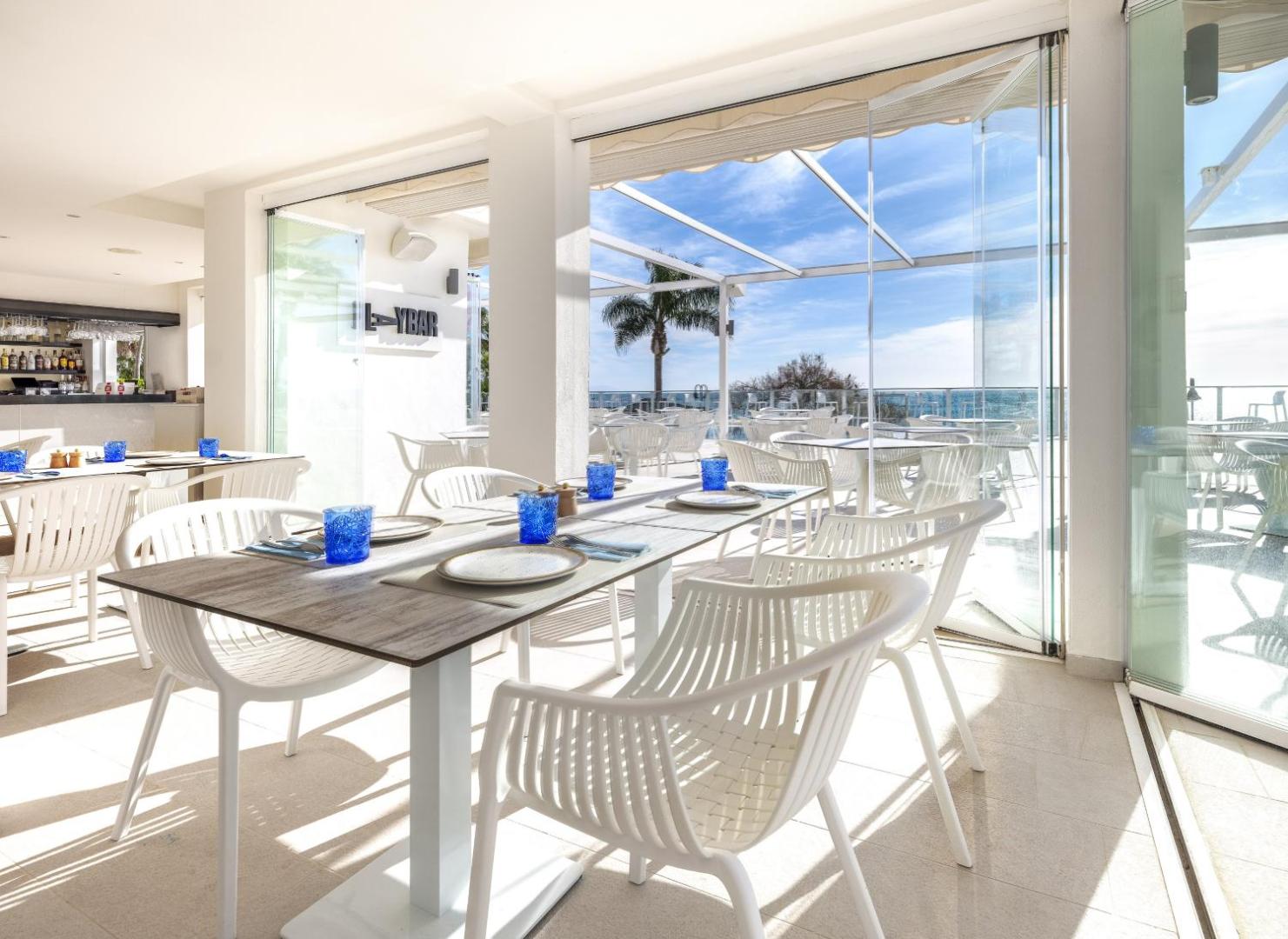 Sol House Costa Del Sol viesnīcas restorāns ar gaišu interjeru, klātiem galdiem un skatu uz Vidusjūru caur lieliem stikla logiem