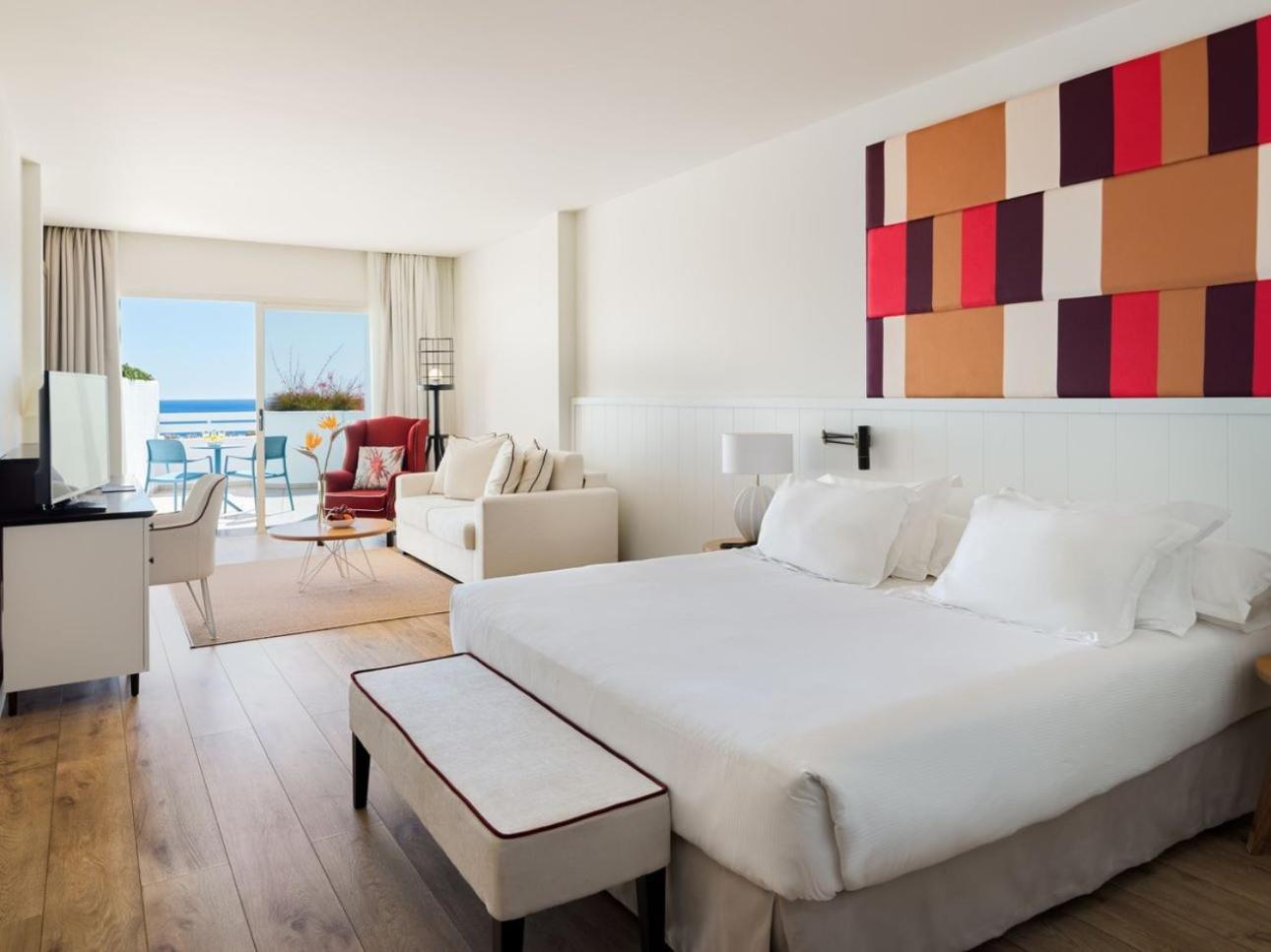 H10 Estepona Palace junior suite numurs ar atpūtas zonu, dīvānu un plašu terasi ar skatu uz zilo jūru