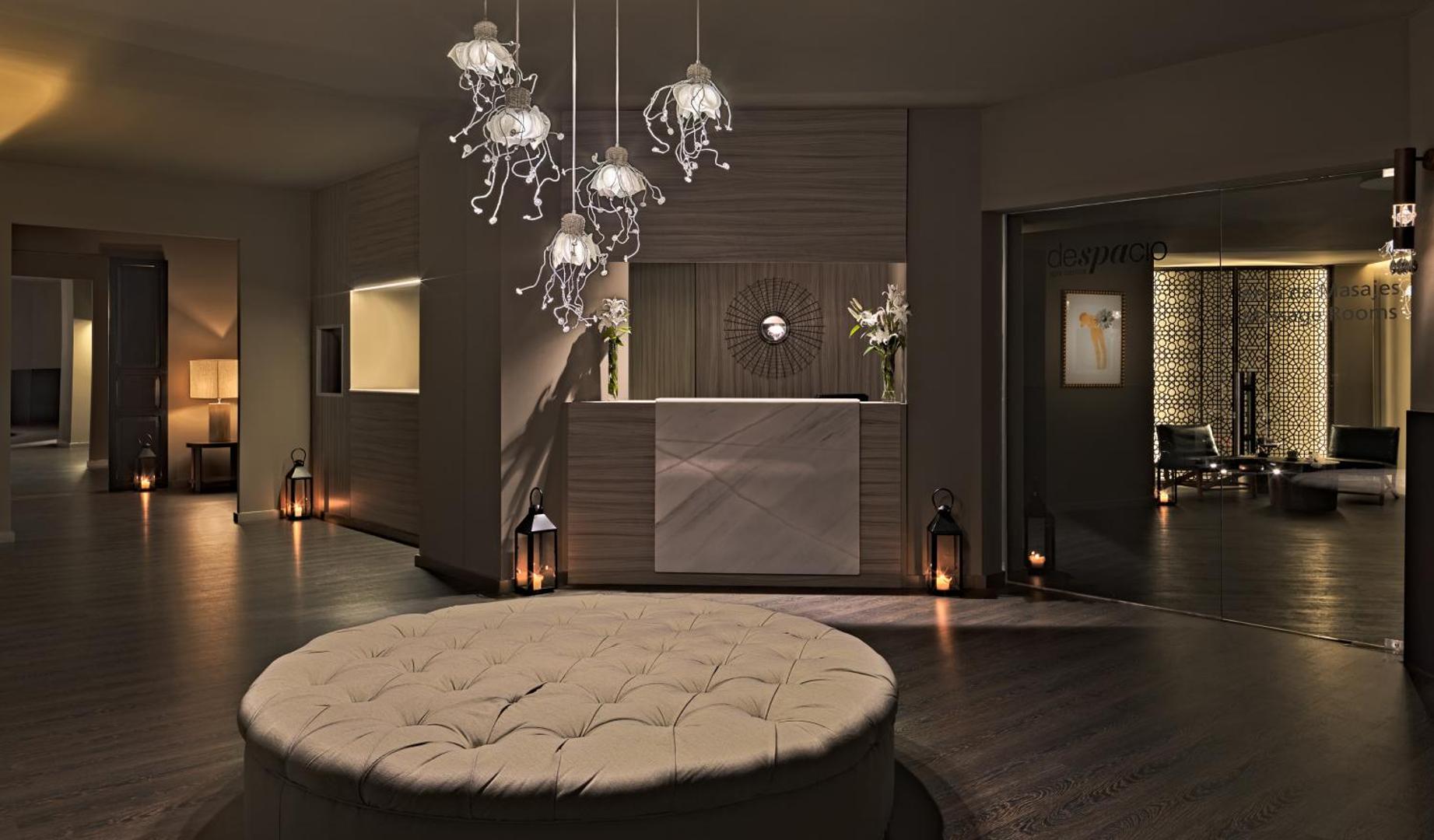 H10 Estepona Palace spa centra uzņemšanas telpa ar mājīgu apgaismojumu, dizaina lampām un elegantu atpūtas zonu