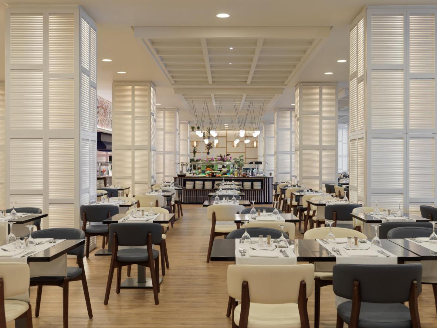 H10 Estepona Palace galvenā restorāna interjers ar gaišām kolonnām, elegantiem galdiem un bufetes zonu fonā.