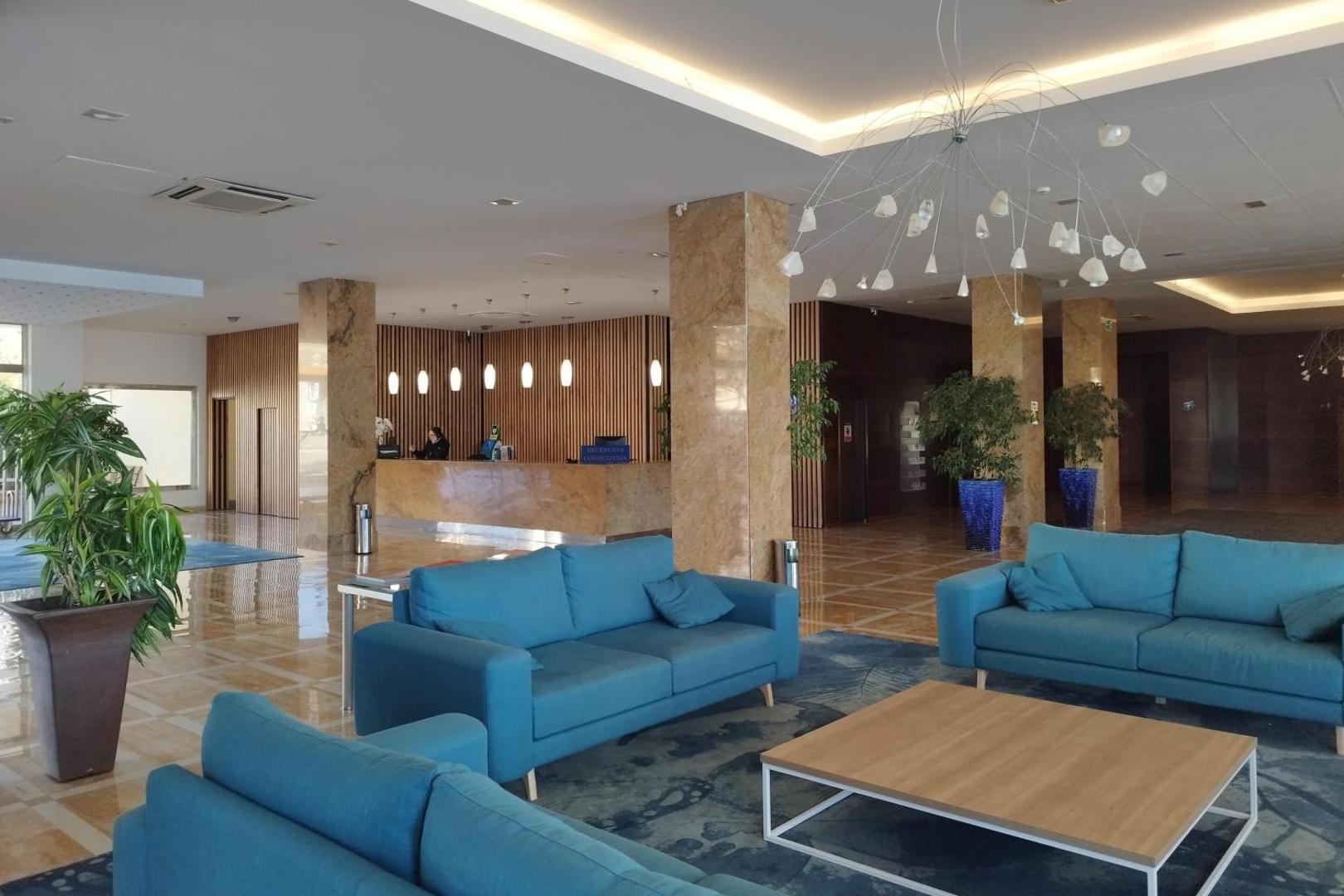 Viesnīcas Best Benalmadena lobby zona ar gaiši ziliem dīvāniem, marmora kolonnām un modernu apgaismojumu Malagas reģionā, Spānijā