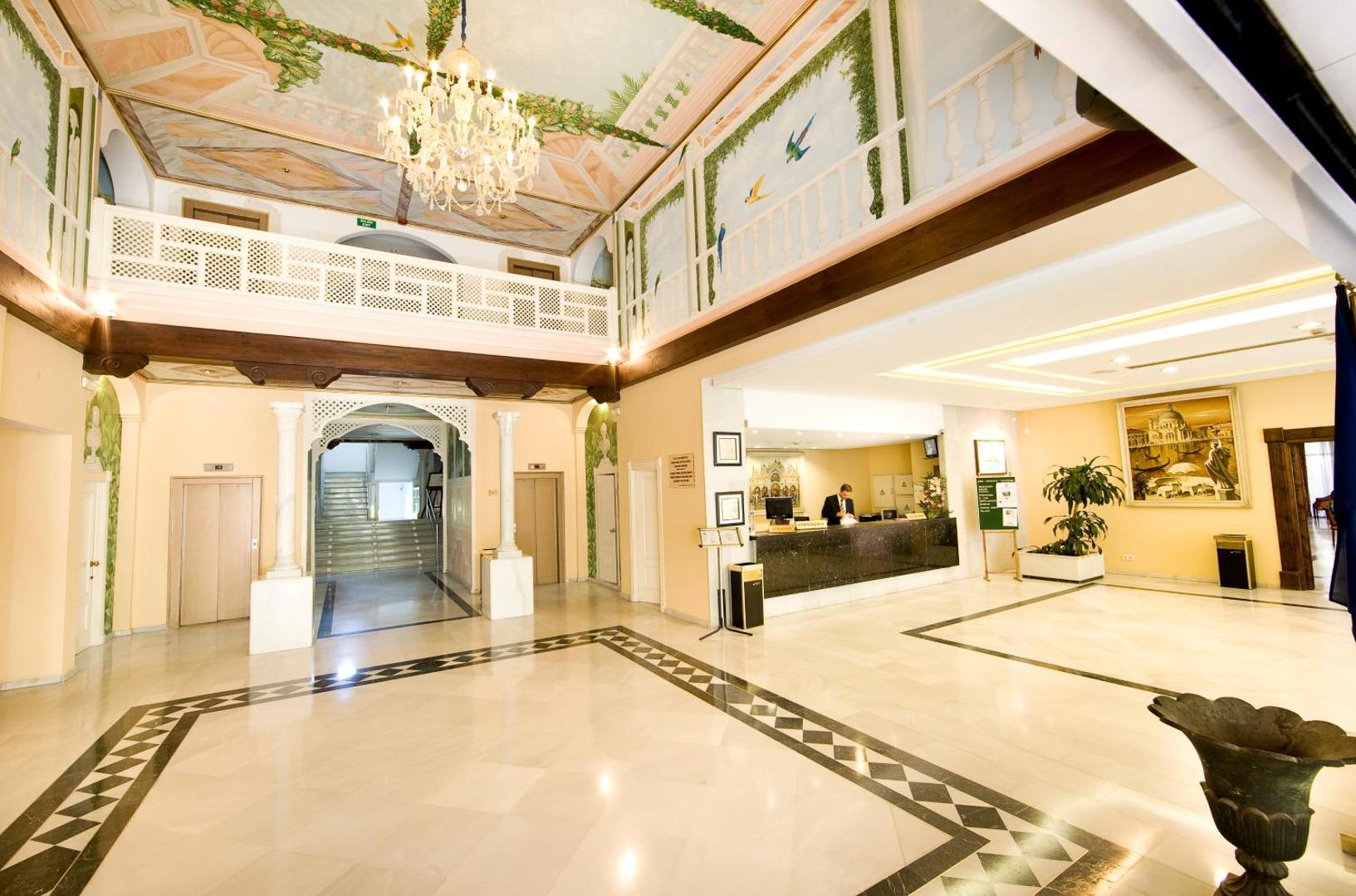 Aparthotel Monarque Sultan plašais vestibils ar marmora grīdu, kristāla lustru un klasiska stila griestu gleznojumiem Marbeljā.
