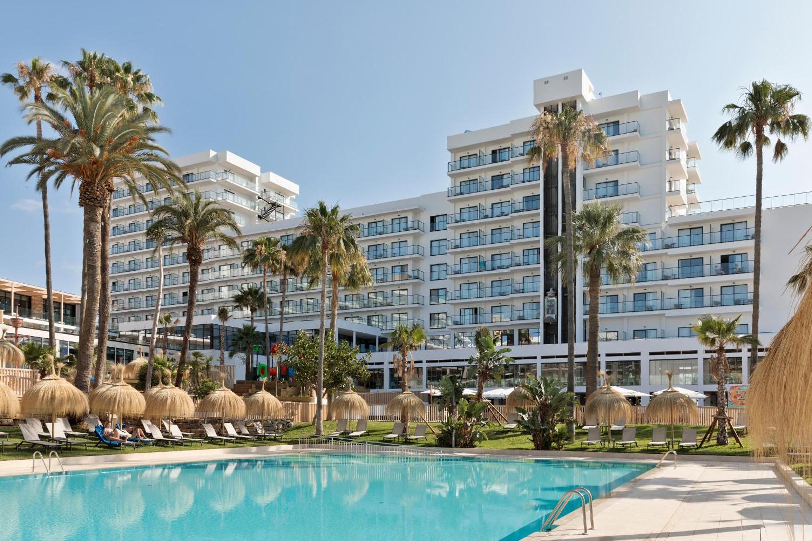 Hotel Best Tritón āra baseins ar ziliem ūdeņiem un atpūtas zonu Benalmadenā, Spānijā — palmas un saulessargi pie viesnīcas ēkas