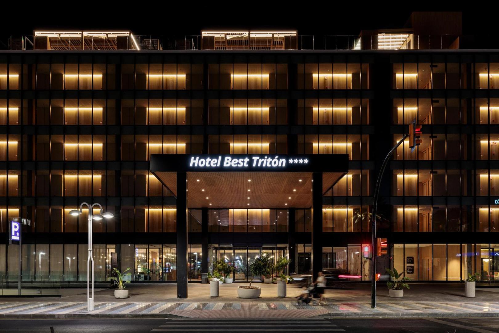 Hotel Best Tritón 4* ieeja nakts apgaismojumā Benalmadenā — moderna fasāde ar siltu gaismu un viesnīcas nosaukumu