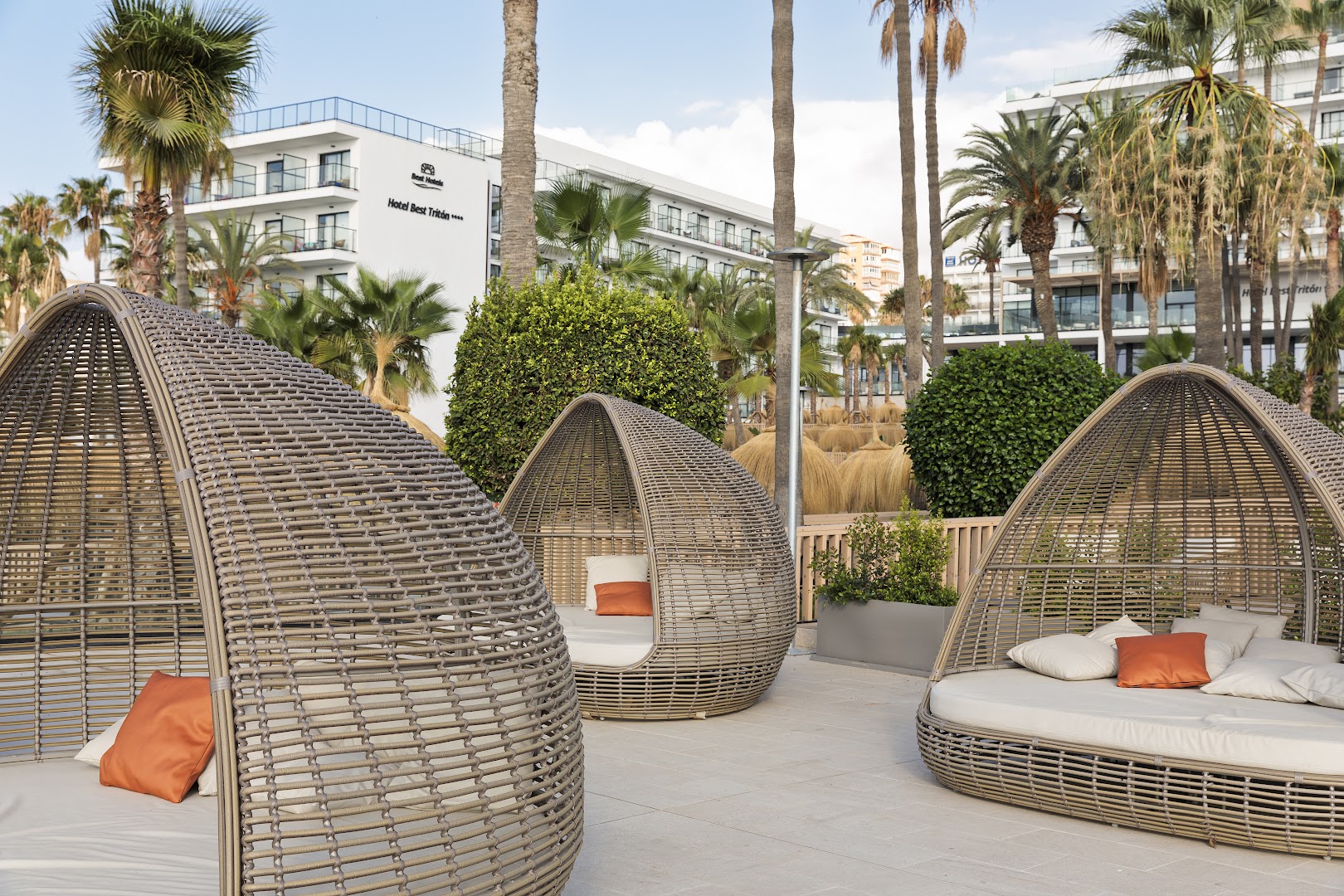 Dizaina atpūtas krēsli Hotel Best Tritón teritorijā Benalmadenā — pītas konstrukcijas ar mīkstiem spilveniem dārza zonā