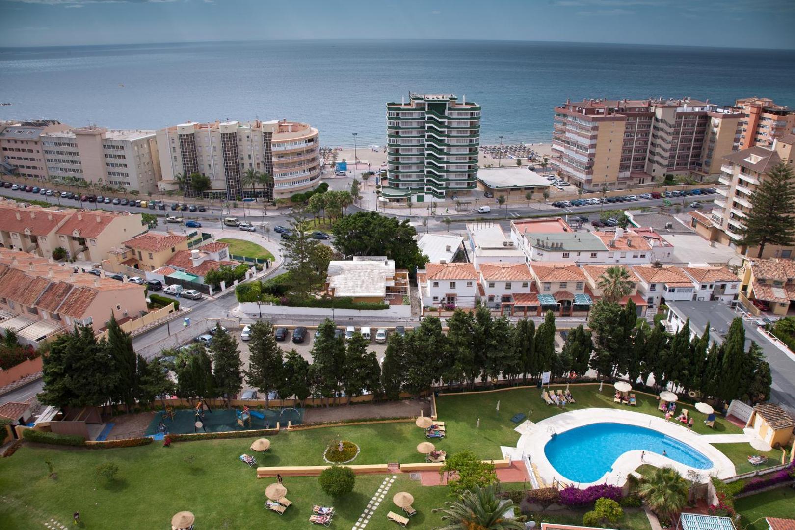Panorāmas skats no Monarque Torreblanca uz āra baseinu, zaļo zonu un pilsētas apbūvi pie Vidusjūras krasta Fuengirolā