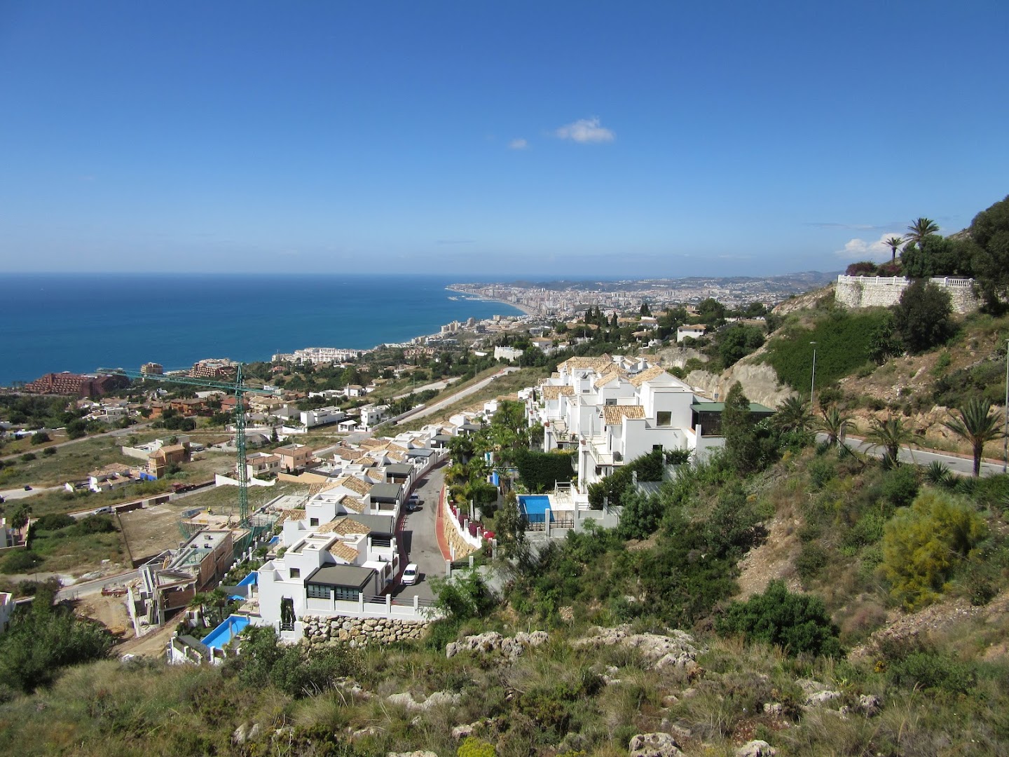 Monarque Torreblanca panorāmas skats no kalna uz Fuengirolas pilsētu un Vidusjūras piekrasti Spānijā ar baltām ēkām un zilu debesu fonu