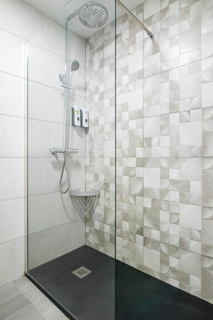 Apartamentos Mediterraneo numura vannasistabas dušas zona ar modernām flīzēm, stikla starpsienu un lietus dušas galvu.