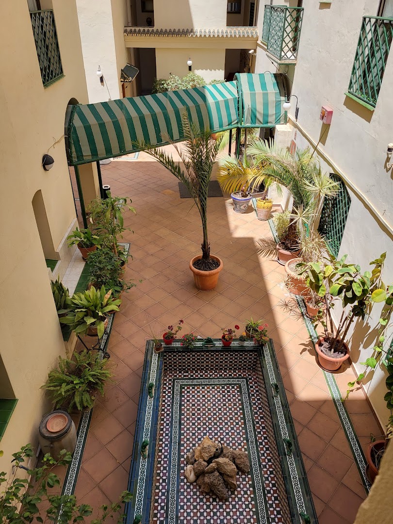 Apartamentos Mediterraneo tradicionālais iekšpagalms ar flīžu mozaīkas dekoru, zaļiem augiem un svītrainu tentu