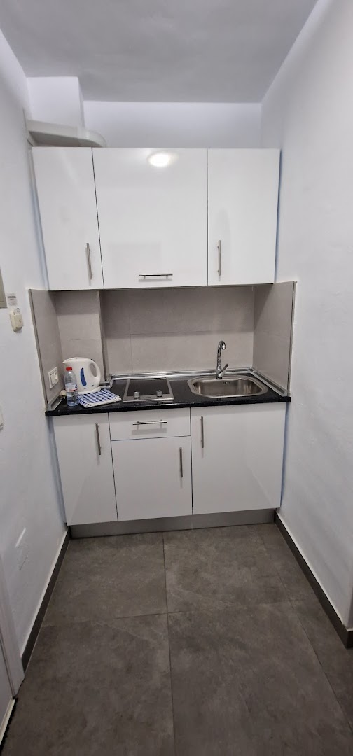 Apartamentos Mediterraneo kompakta virtuves zona ar izlietni, plīts virsmu un tējkannu — praktisks risinājums nelielā telpā