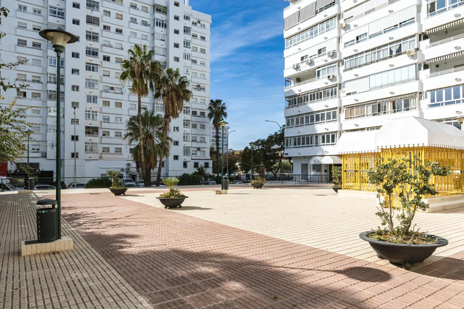 Apartamentos Mediterraneo bruģētais laukums starp viesnīcas ēkām ar dekoratīviem augiem podos un modernu apgaismojumu