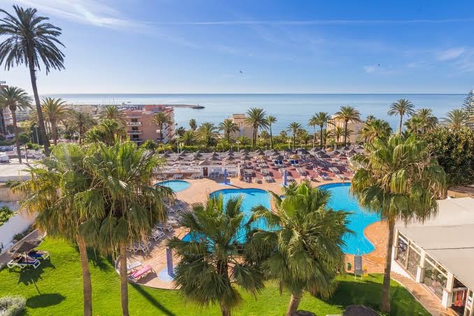 Best Siroco viesnīcas panorāmas skats uz baseinu kompleksu un Vidusjūru Benalmadenā, Spānijā — palmas, sauļošanās terases un dārza zona