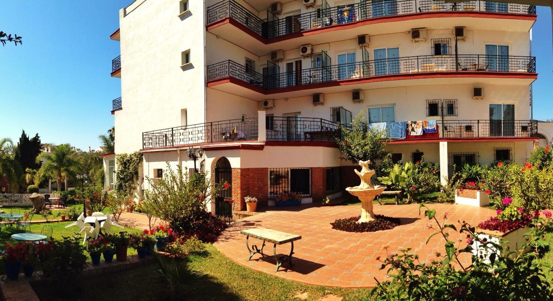Hotel Carmen Teresa iekšpagalms ar flīzētu terasi, nelielu strūklaku, dārza mēbelēm un numuru balkoniem