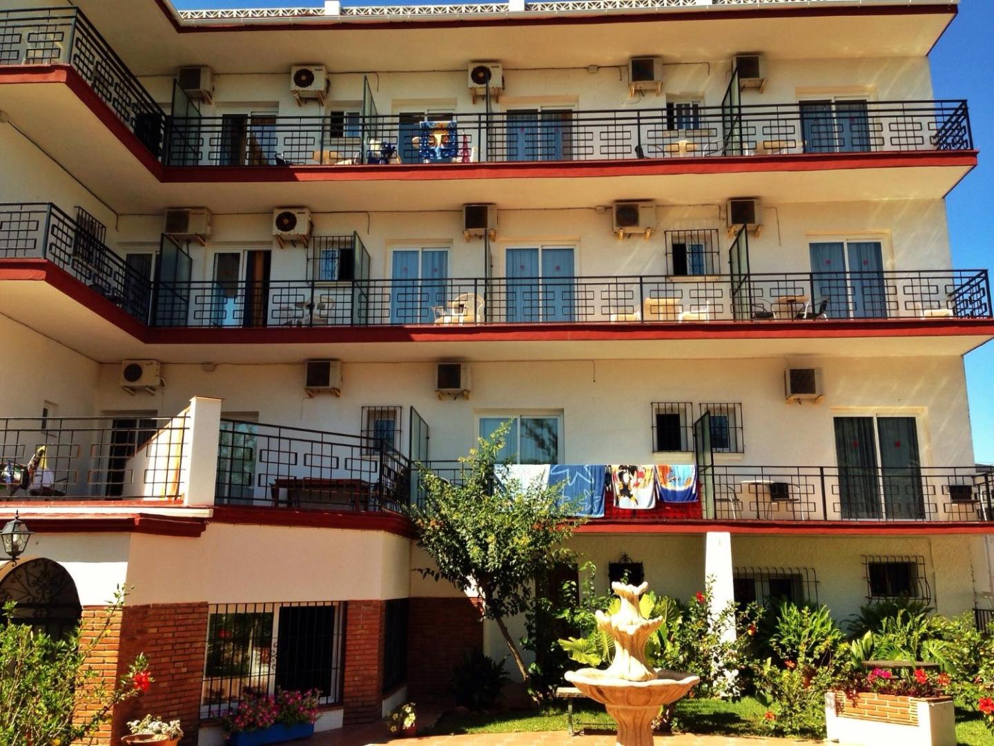 Hotel Carmen Teresa ēkas korpuss ar balkoniem, gaisa kondicionieriem un iekšpagalma strūklaku dārza ielokā