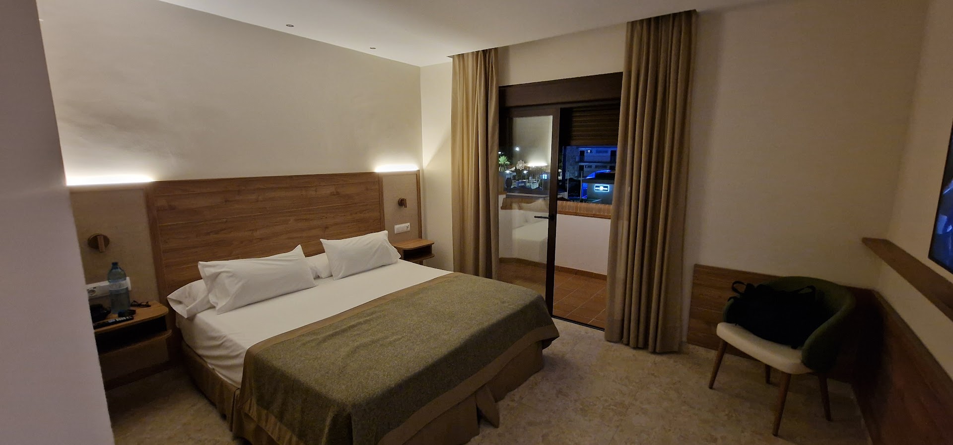 Tarik Hotel moderns divvietīgs numurs ar koka apdari, lielu gultu un izeju uz balkonu vakarā Torremolinosā, Spānijā.