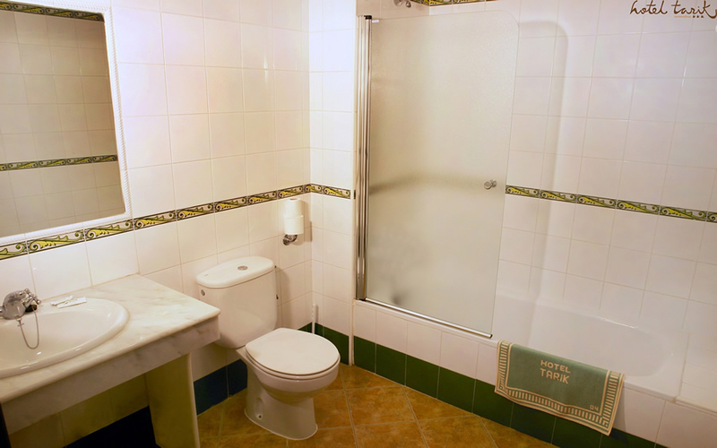 Tarik Hotel numura vannas istaba ar vannu, dušas sienu un marmora virsmas izlietni — gaišs un tīrs interjers