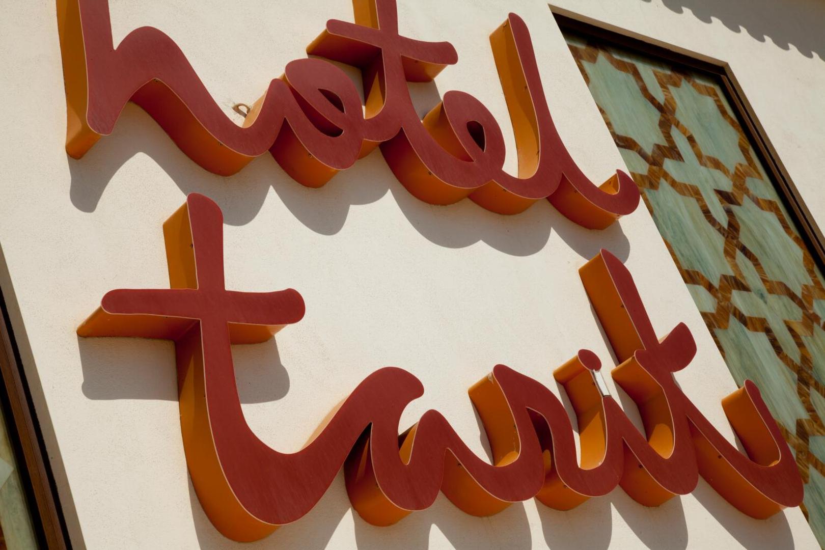 Viesnīcas Hotel Tarik izkārtne pie ēkas fasādes Torremolinosā — retro stila sarkani burti uz gaiša sienas fona