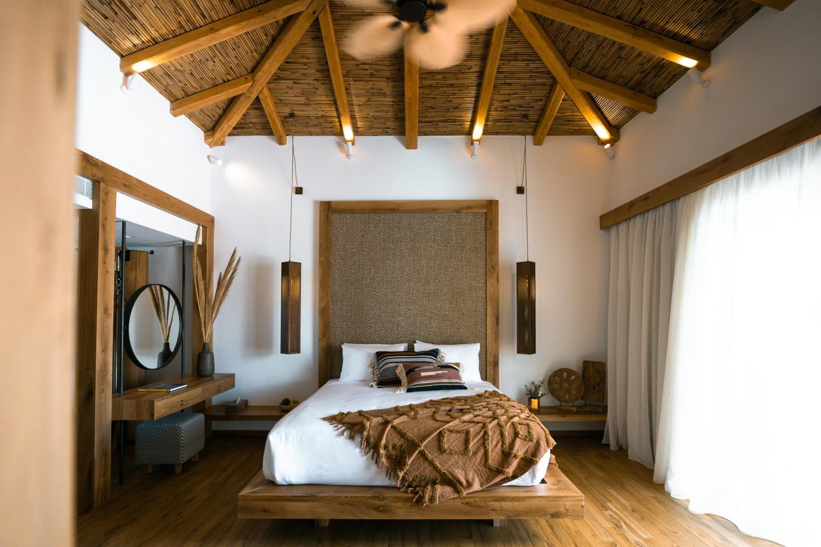 Stella Island Luxury Resort & Spa numurs ar augstiem bambusa griestiem, koka apdari un dabisku materiālu interjeru