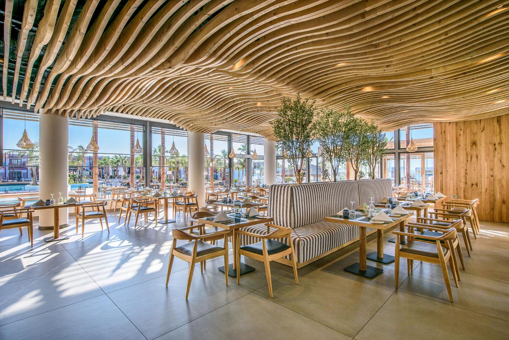 Stella Island Luxury Resort & Spa moderns restorāns ar dizaina koka griestiem un skatu uz baseinu