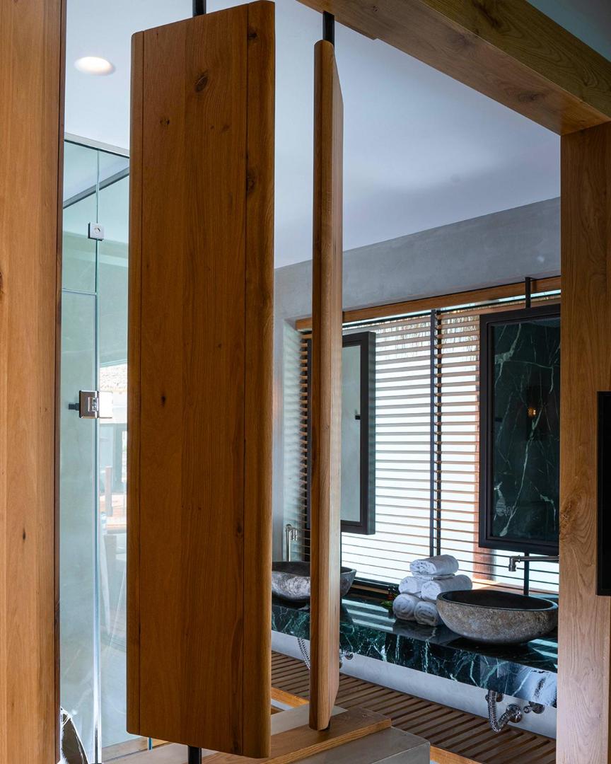 Stella Island Luxury Resort & Spa vannas istabas interjers ar akmens izlietnēm, koka apdari un modernu dizainu Krētā