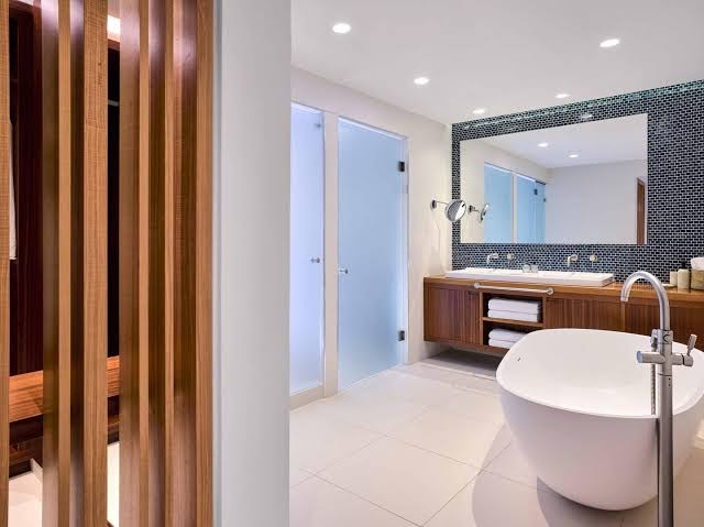 Grecotel Lux Me White Palace luksusa numura vannas istaba ar brīvi stāvošu vannu, koka apdari un modernu dizainu
