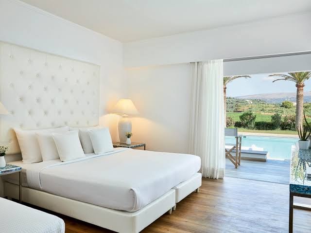 Grecotel Lux Me White Palace numurs ar izeju uz koplietošanas baseinu un dārzu — elegants dizains ar koka grīdu
