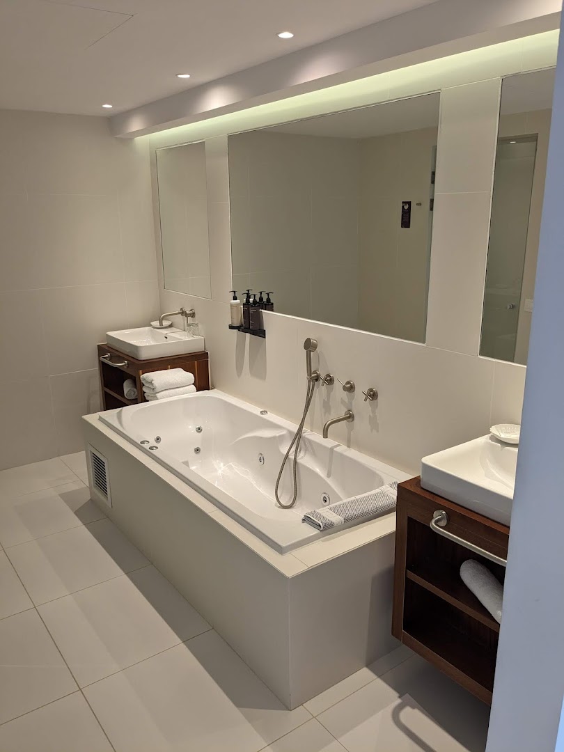 Grecotel Lux Me White Palace numura vannas istaba ar džakuzi vannu, divām izlietnēm un gaišu interjeru