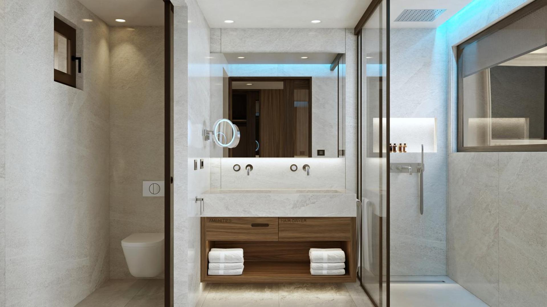 Nana Royal Premium Resort vannas istabas interjers ar dubulto izlietni, lielu spoguli un stiklotu dušas zonu gaišos toņos