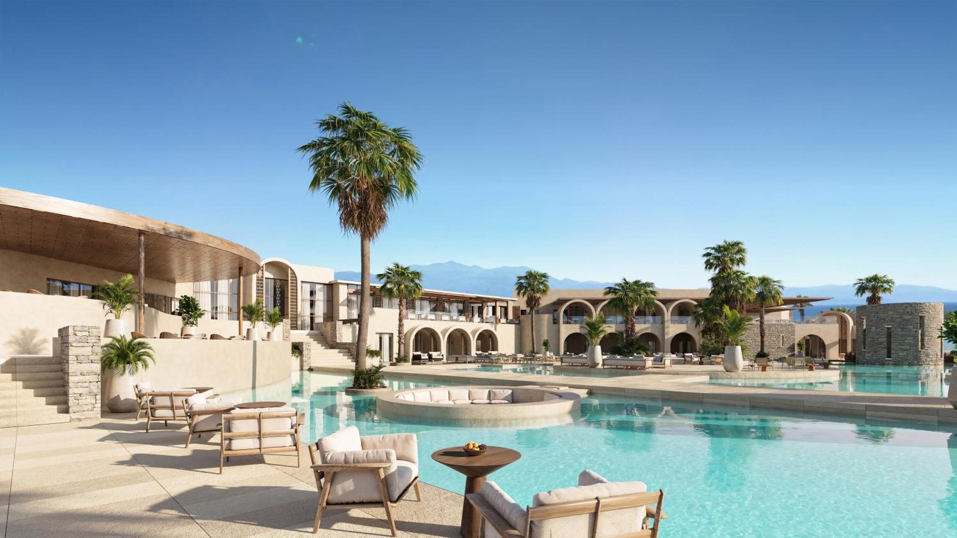 Nana Royal Premium Resort plašais āra baseins ar atpūtas zonu un palmām Krētā — skats uz viesnīcas arhitektūru un kalniem tālumā