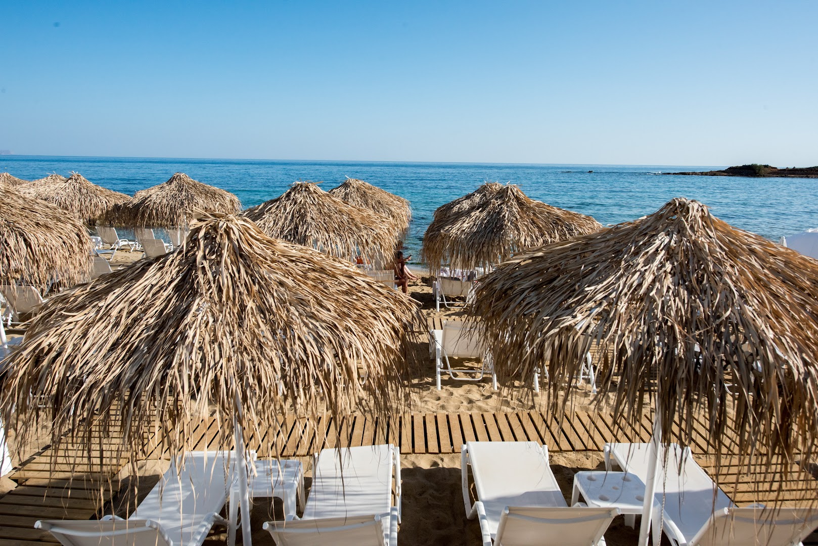 Viesnīcas Enorme Ammos Beach Resort privātā pludmales zona ar daudziem salmu saulessargiem un koka laipām smiltīs